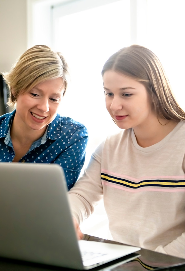 teenage girl sitting in front of computer with mother applying for a student loan