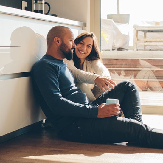 happy couple relaxing on floor in newly remodeled kitchen