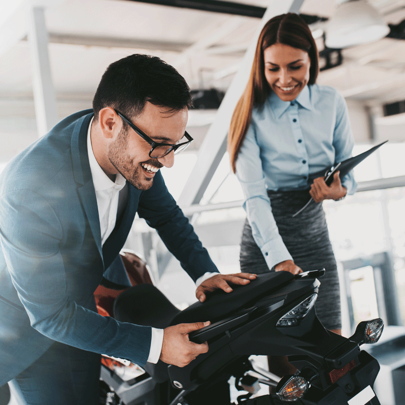 happy man with female salesperson asking questions about buying a new motorcycle