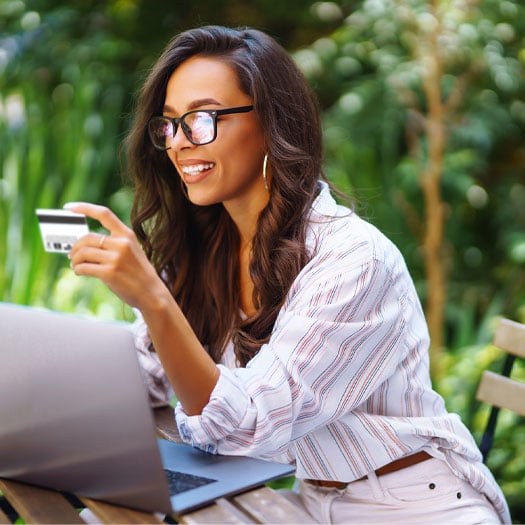 woman sitting in front of laptop viewing a credit held in her left hand