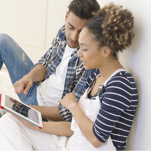 couple covered in paint looking at heloc terms on a tablettablet 