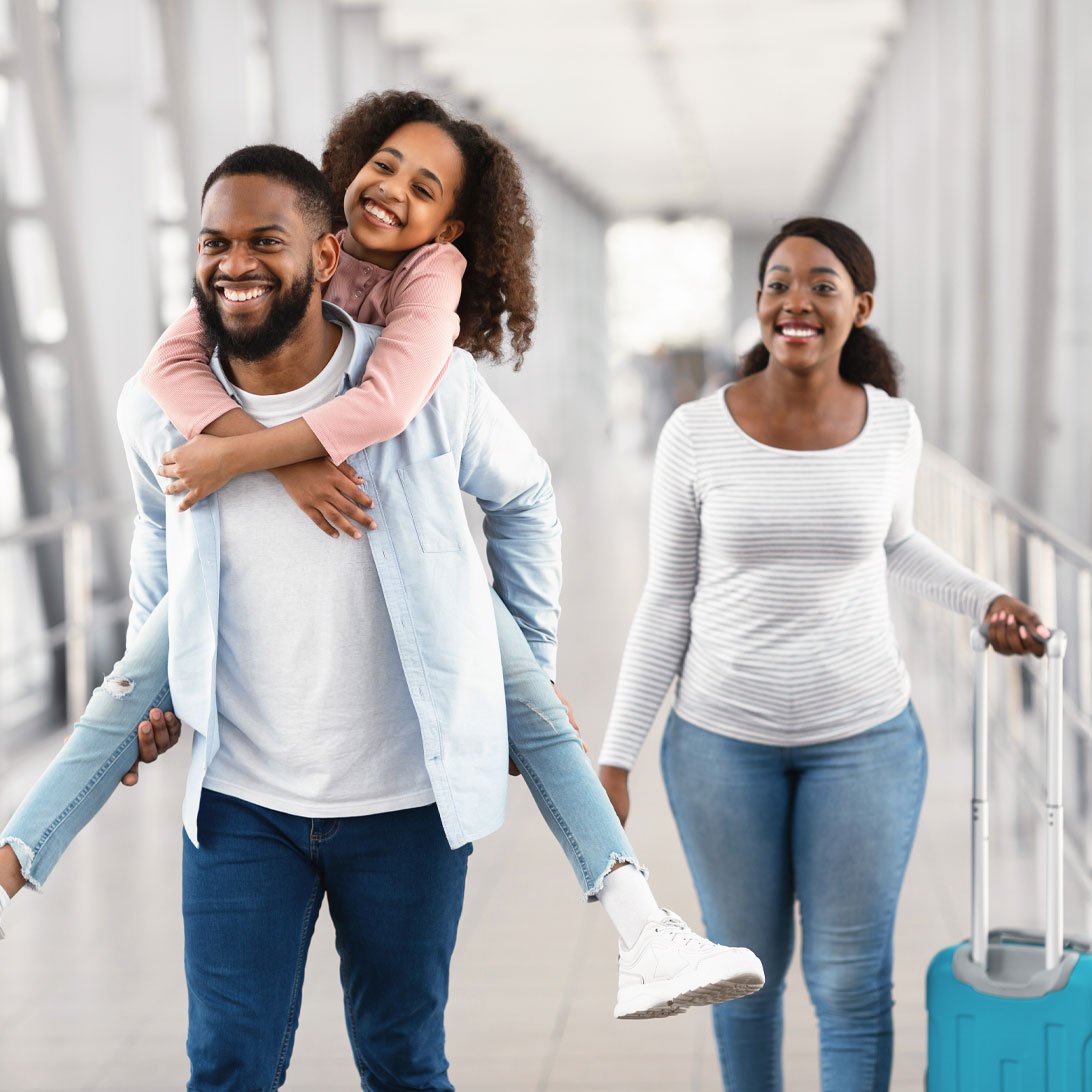 young girl hanging on her fathers back with mother walking next to them 