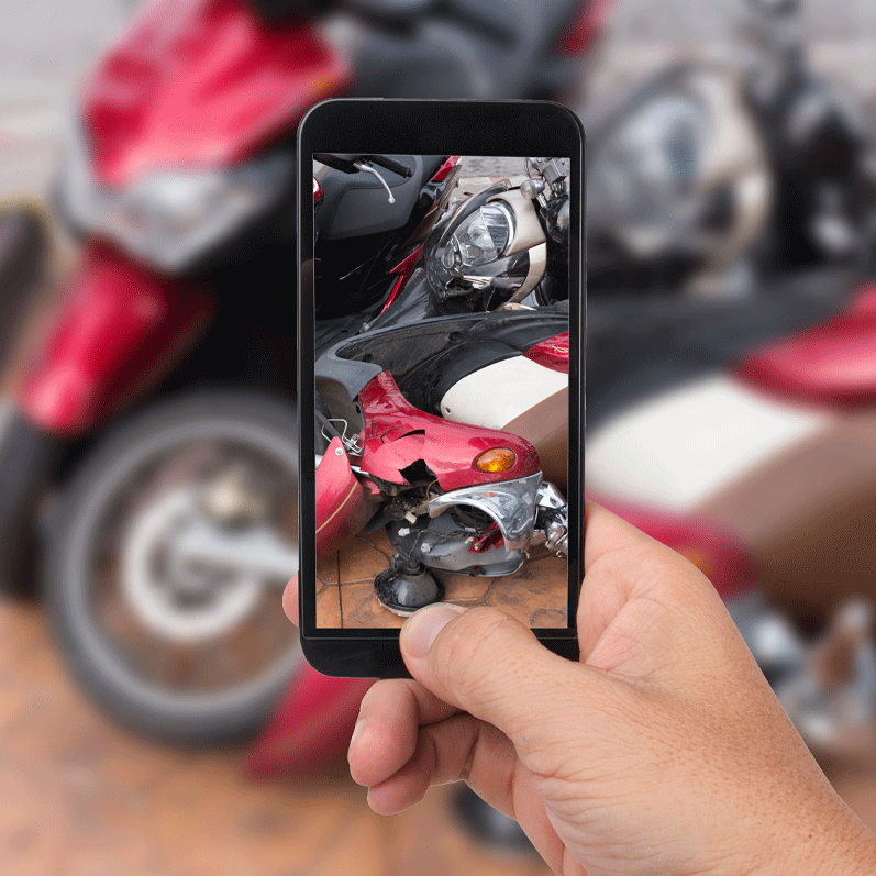 man taking photo with cell phone of motorcycle accident