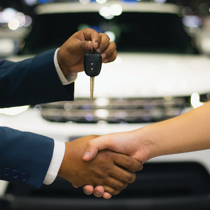 Car dealer handing keys to member with handshake