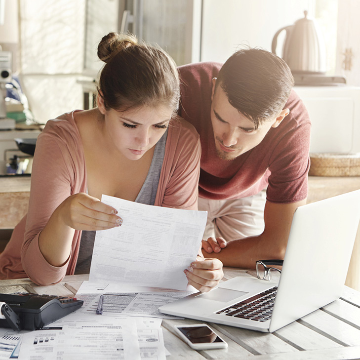 Young couple looking at statement in front of laptop