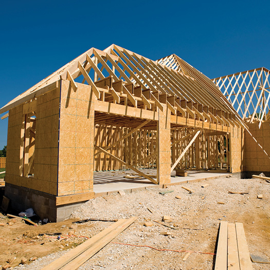 Structure of home being built on dirt lot with two main entry ways facing forward