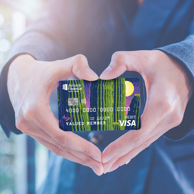 Woman making heart hands with Arizona Financial debit card