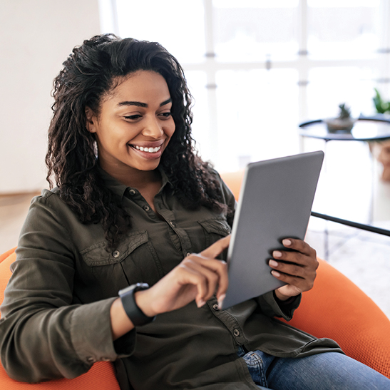 young woman sitting while looking at her money market account on tablet