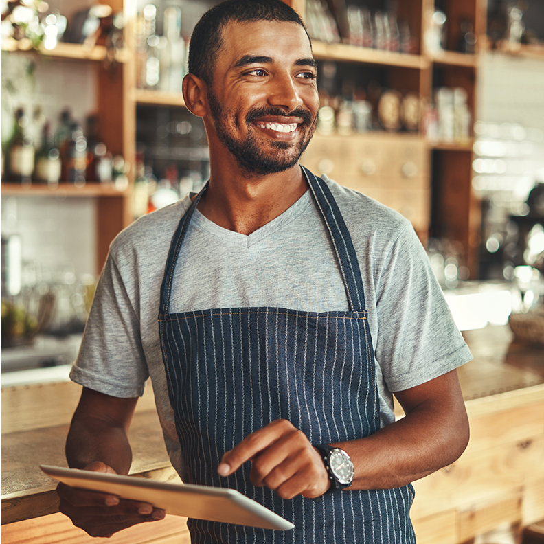 male small business owner smiling with tablet in his hand