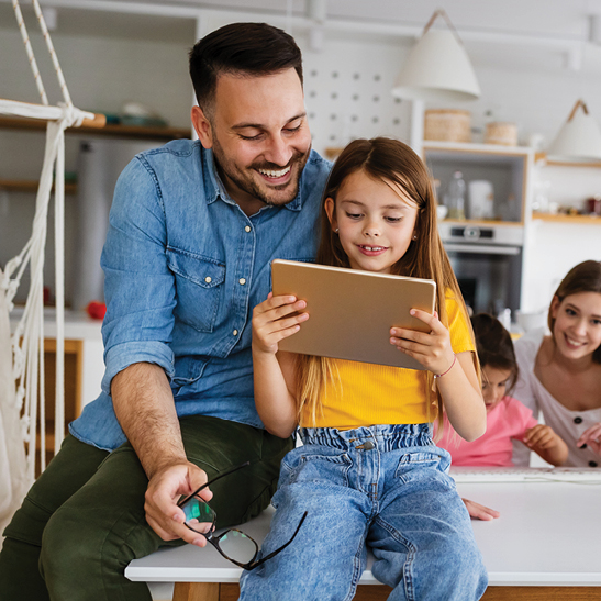 man sitting next to young girl holding a tablet 