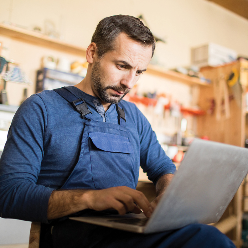 man on laptop in workshop looking at business money market