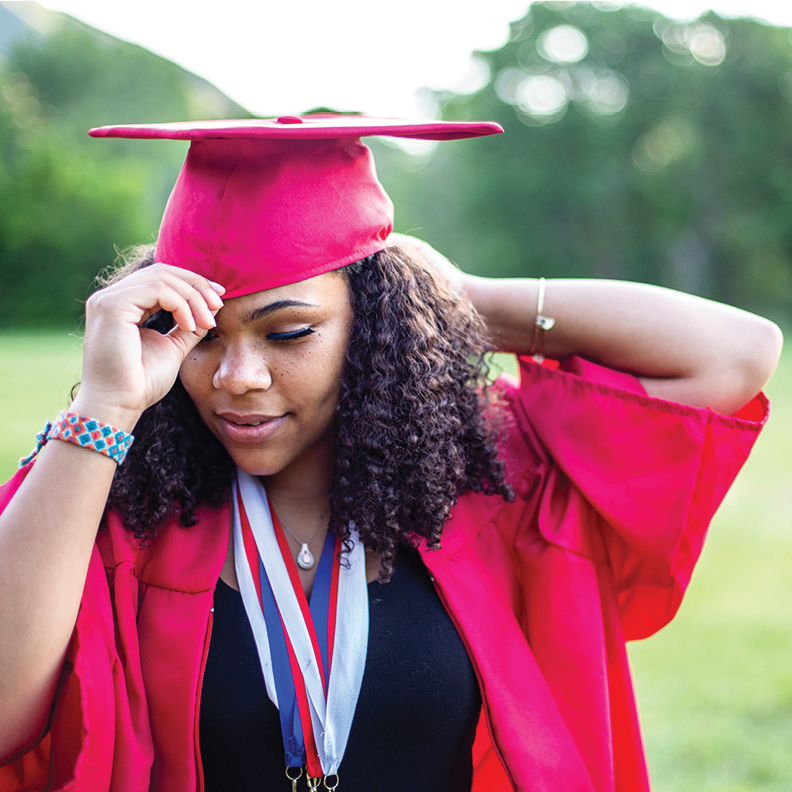 female young adult adjusting her cap and gown for graduation
