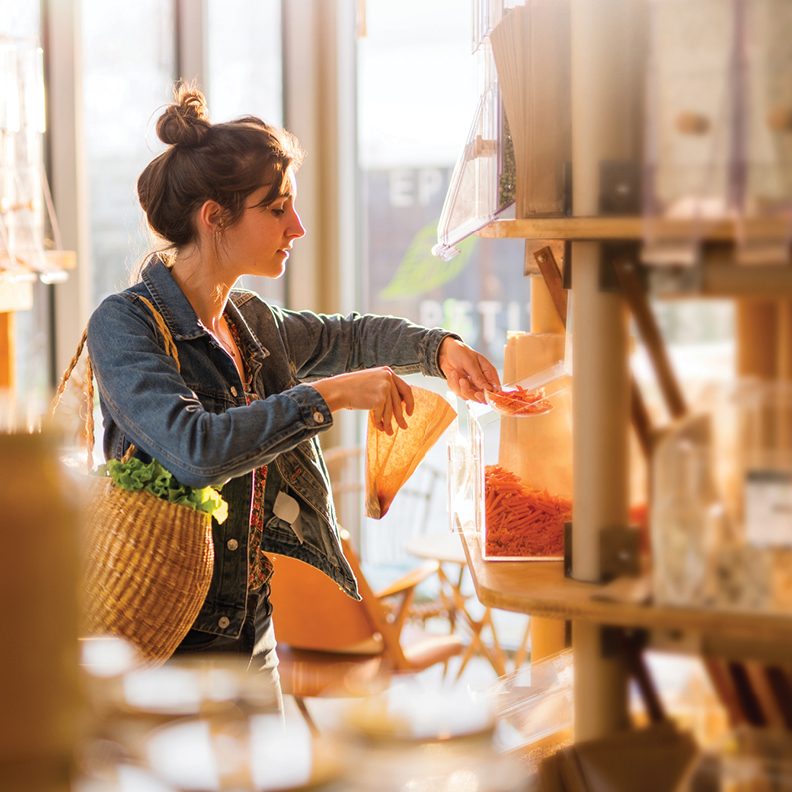 young lady scooping dried bulk food into a brown bag