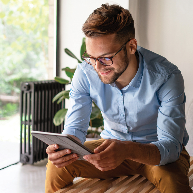 man sitting while opening a savings account on a tablet