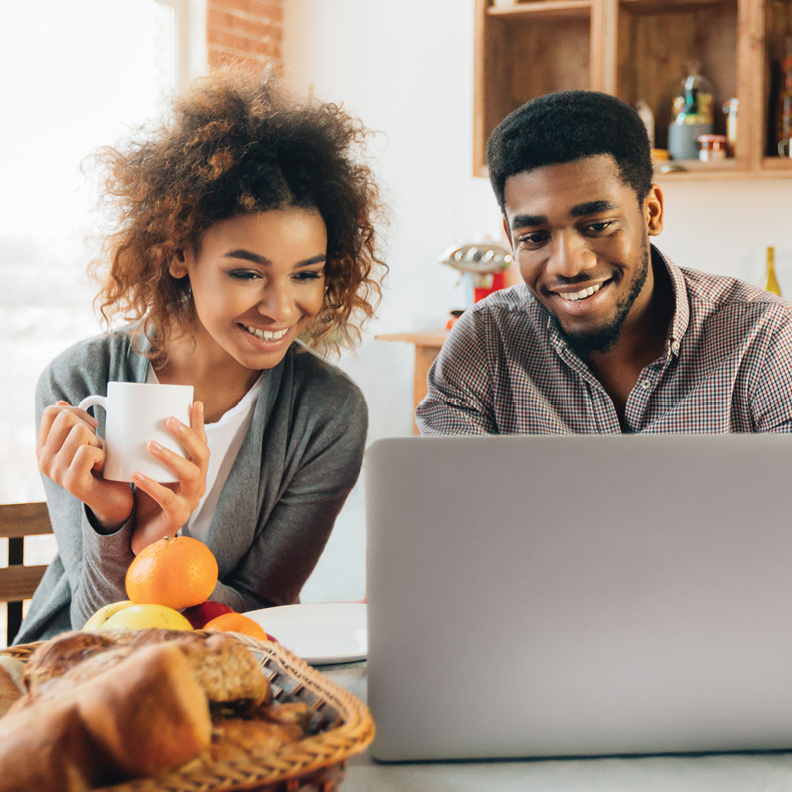 happy couple sitting in front of a laptop reviewing their credit score for a personal loan