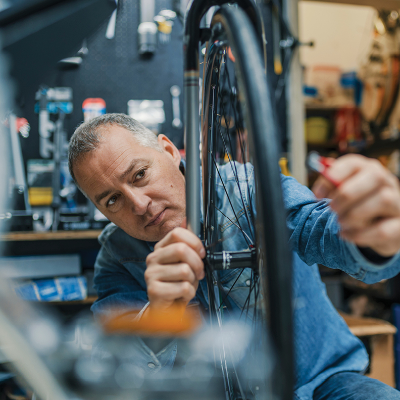 closeup of man working on a bicycle wheel 