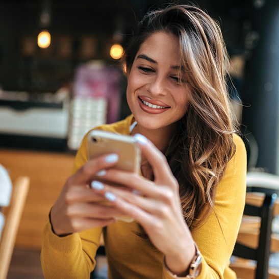 woman on mobile phone smiling at how easy it is to open a checking account online 