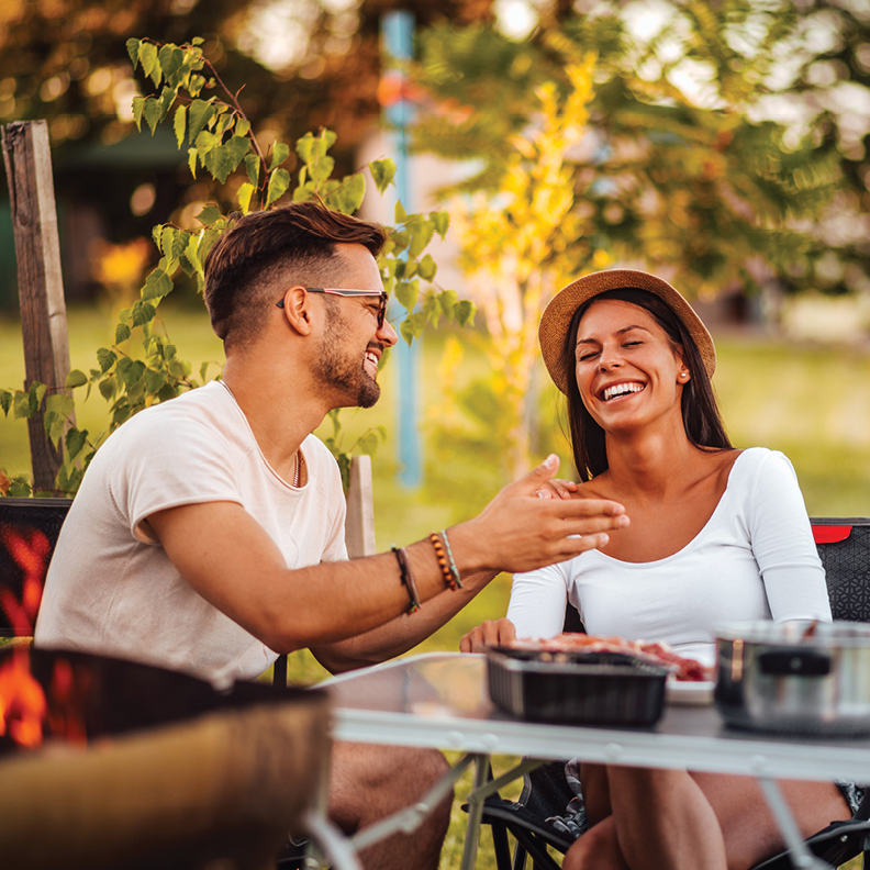 young man and woman smiling at a table outdoors after having their debt cancelled