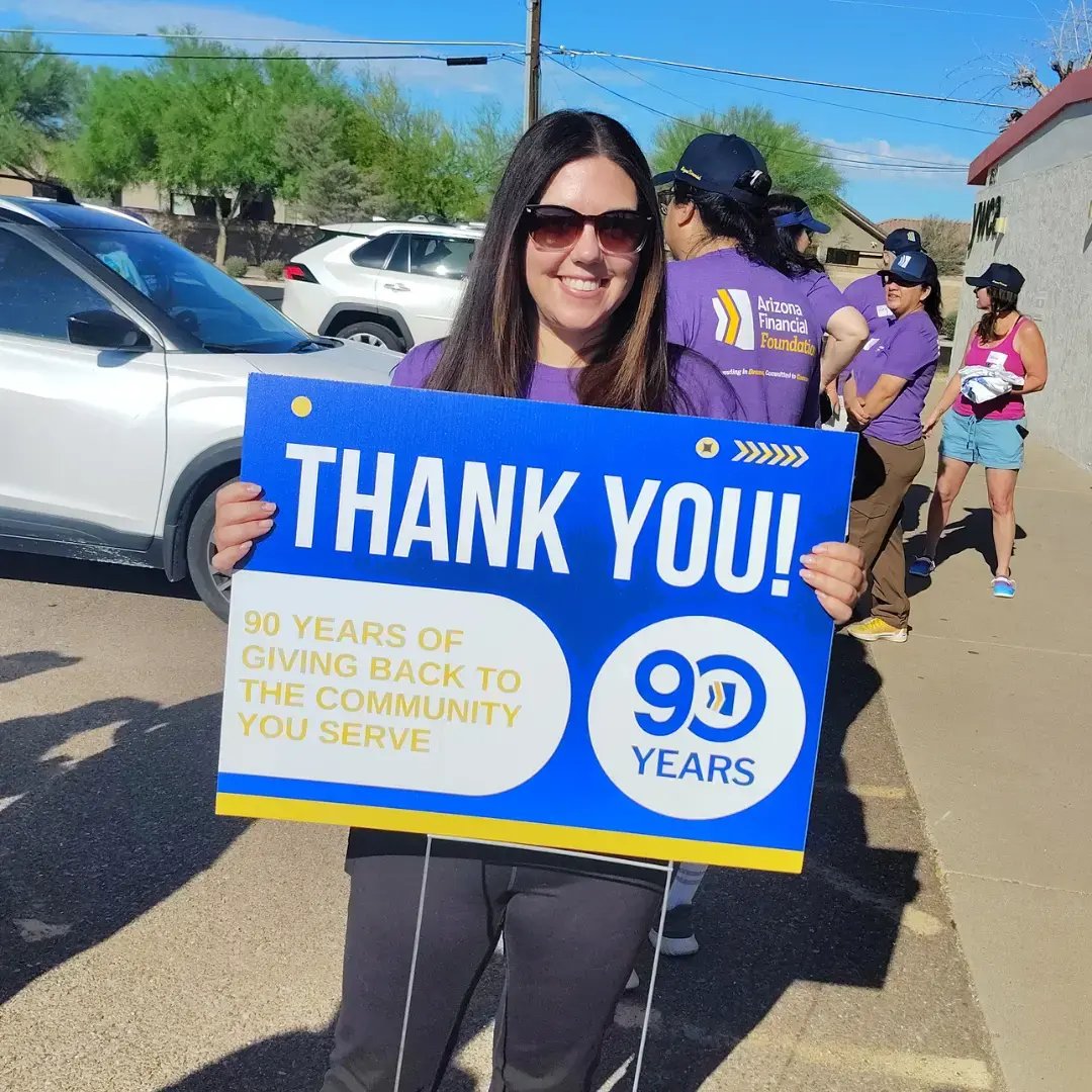 Employee of Arizona Financial smiling and holding up a sign that says thank you for 90 years