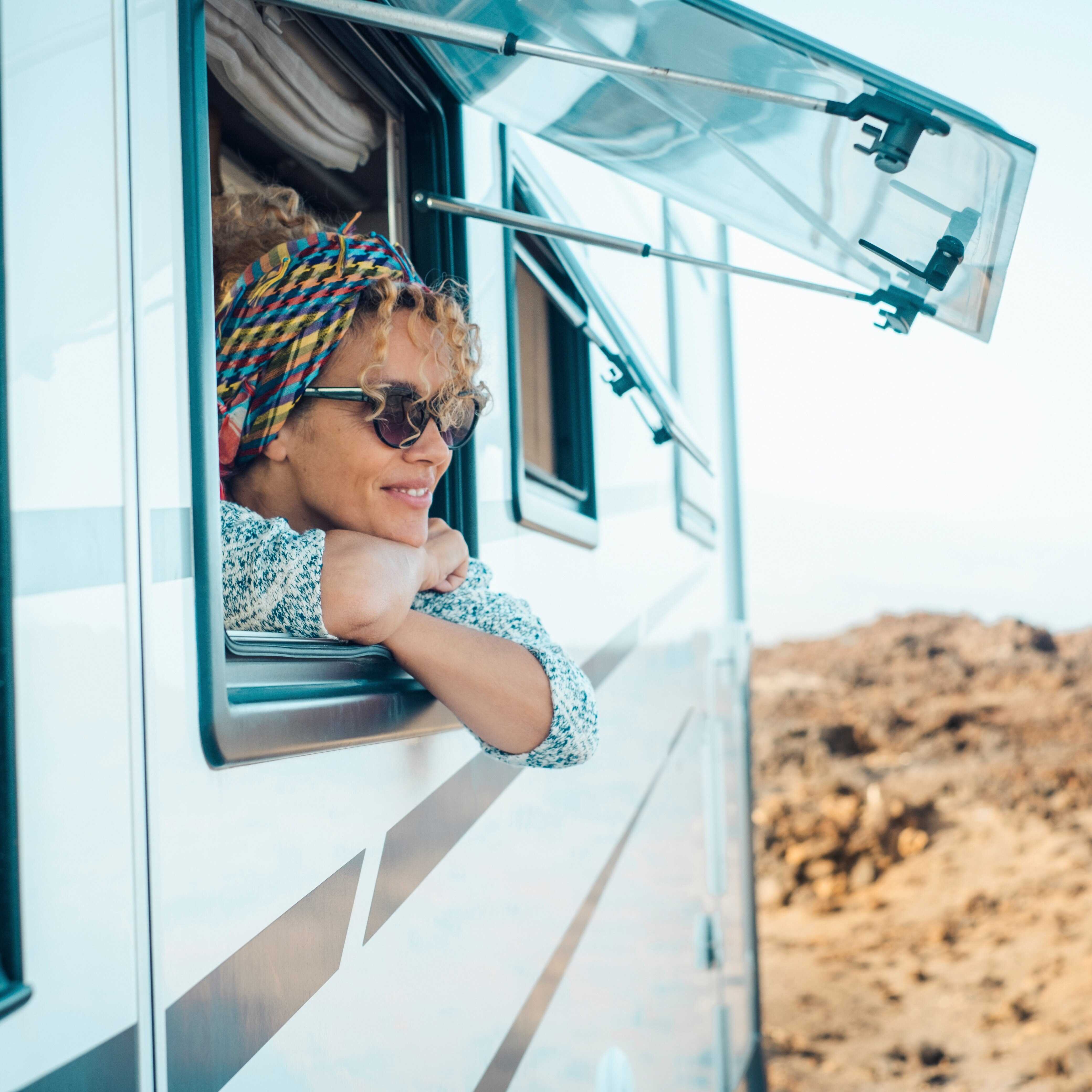 woman staring out of rv window and smiling